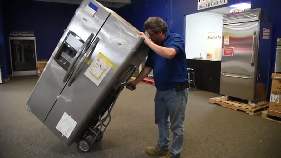An Ava's Moving Service crew carrying a wrapped dresser into a Providence home